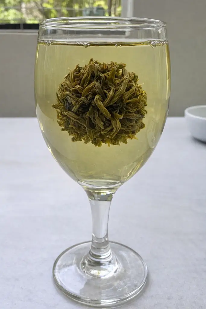 Boule de thé vert nature infusée dans une tasse en porcelaine