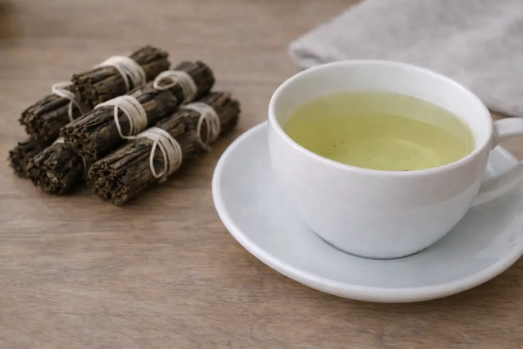 Infusion claire de thé vert en rouleaux dans une tasse en porcelaine